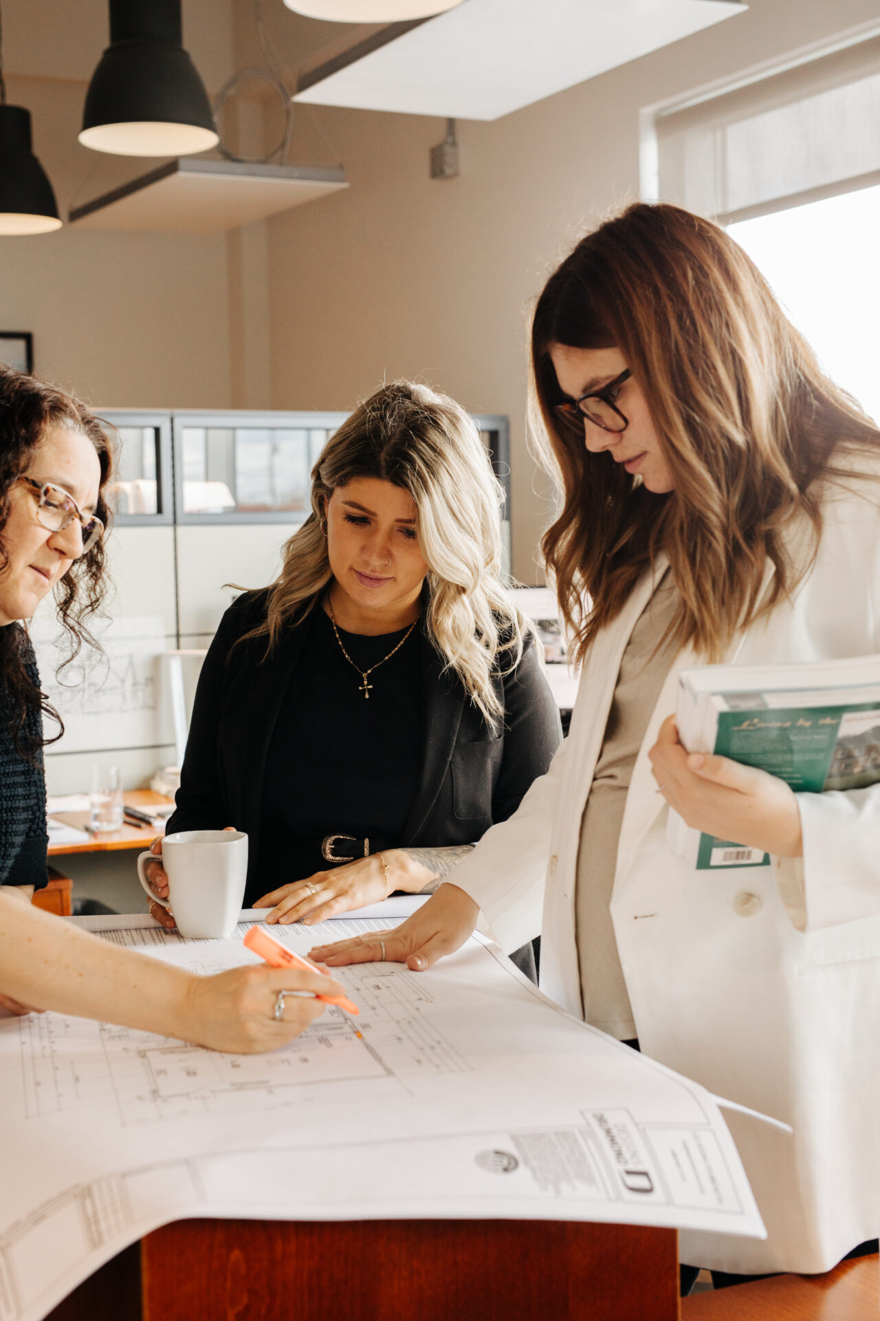 Équipe de technologues en architecture et concepteurs résidentiels analysant un plan de maison personnalisé afin d’optimiser dimensions, fonctionnalité et adaptation aux besoins du client