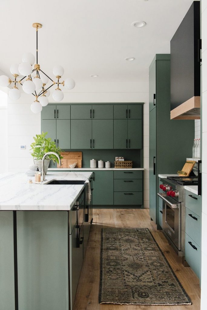 luminaire moderne blanc, armoire cuisine verte, comptoir marbre, plancher bois et superbe tapis de cuisine