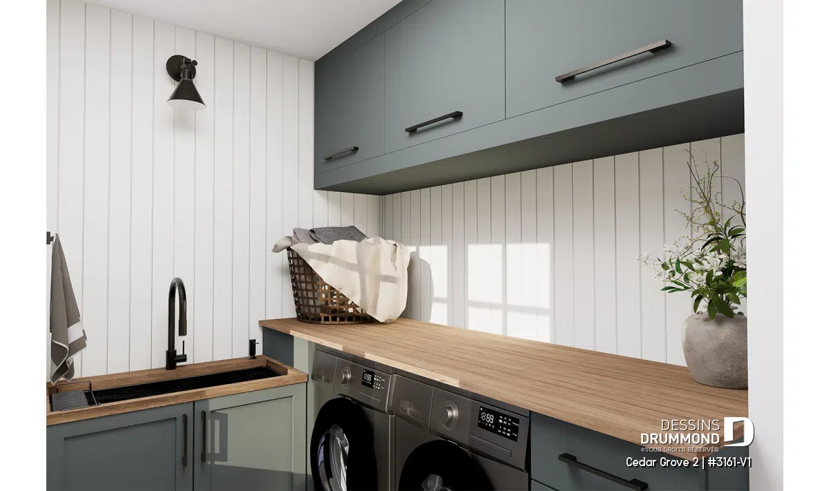 Salle de lavage au rez-de-chaussée du plan Cedar Grove 2 (#3161-V1) avec comptoir en bois, armoires vert sauge et évier utilitaire, style farmhouse moderne.