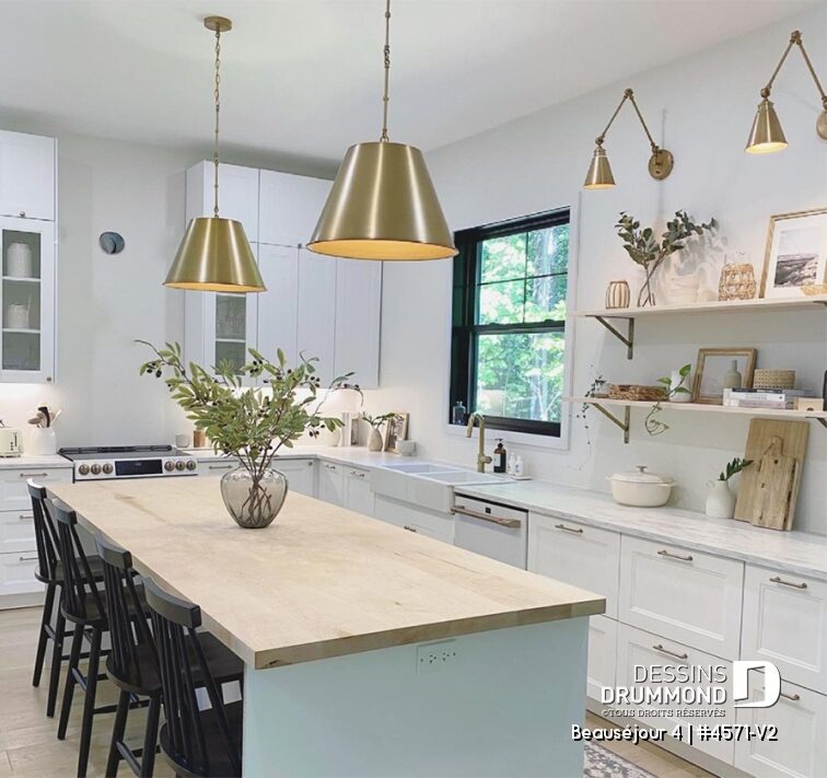 Cuisine de maison de campagne moderne avec grand îlot en bois, armoires blanches et décoration chaleureuse
