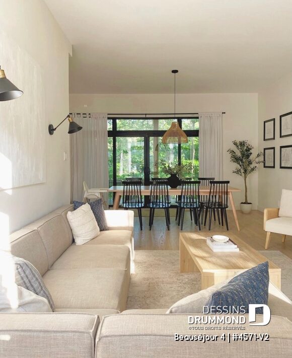 Salon de maison de campagne moderne avec grandes fenêtres, mobilier aux tons naturels et vue sur la salle à manger